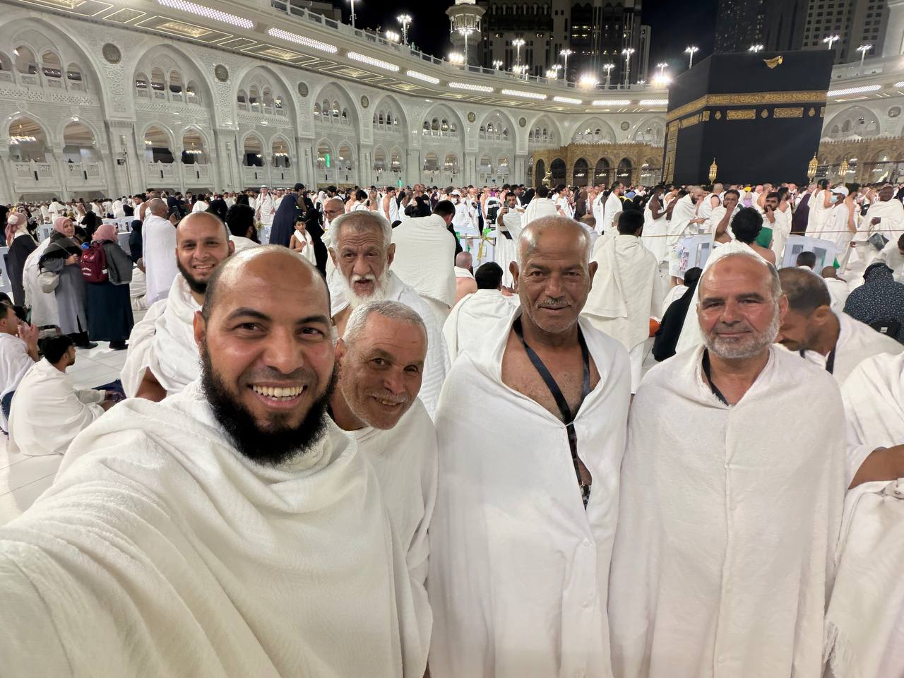 حجاج من كبار السن أمام الكعبة المشرفة ليلًا