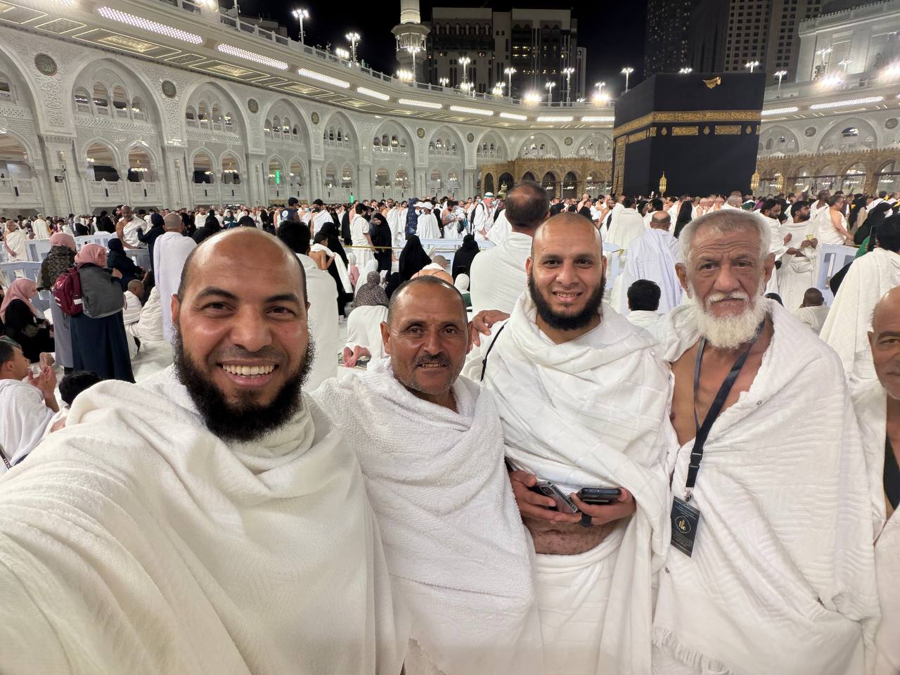 مجموعة من الحجاج مع فريق الإشراف أمام الكعبة المشرفة
