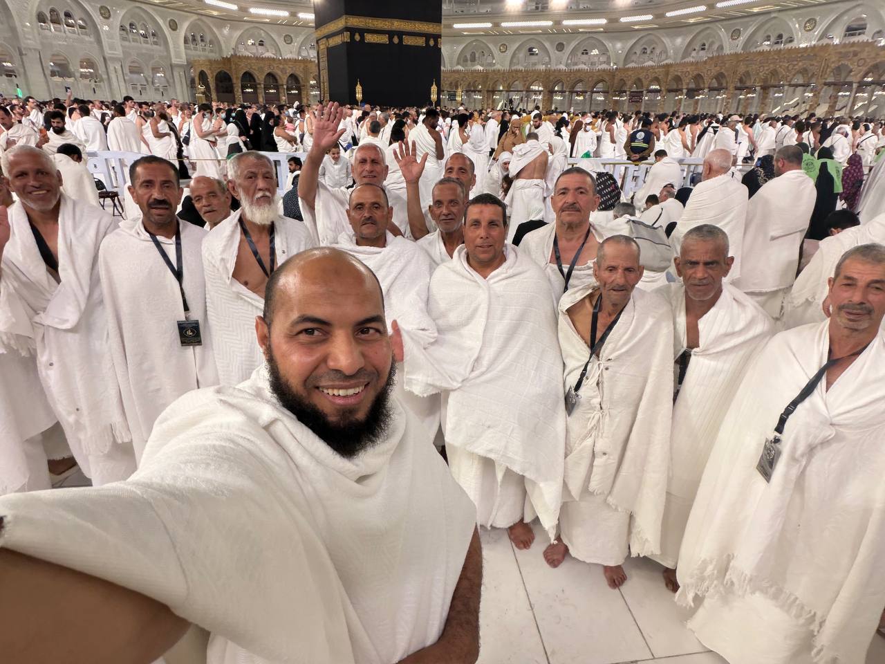 مجموعة من المعتمرين مع فريق الإشراف أمام الكعبة المشرفة